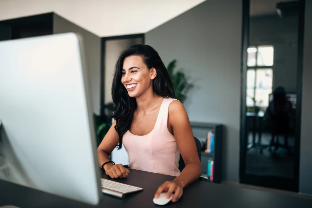 Woman smiling whilst working at a computer