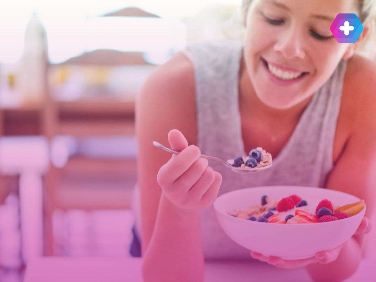 woman eating fruit out of a bowl with a spoon