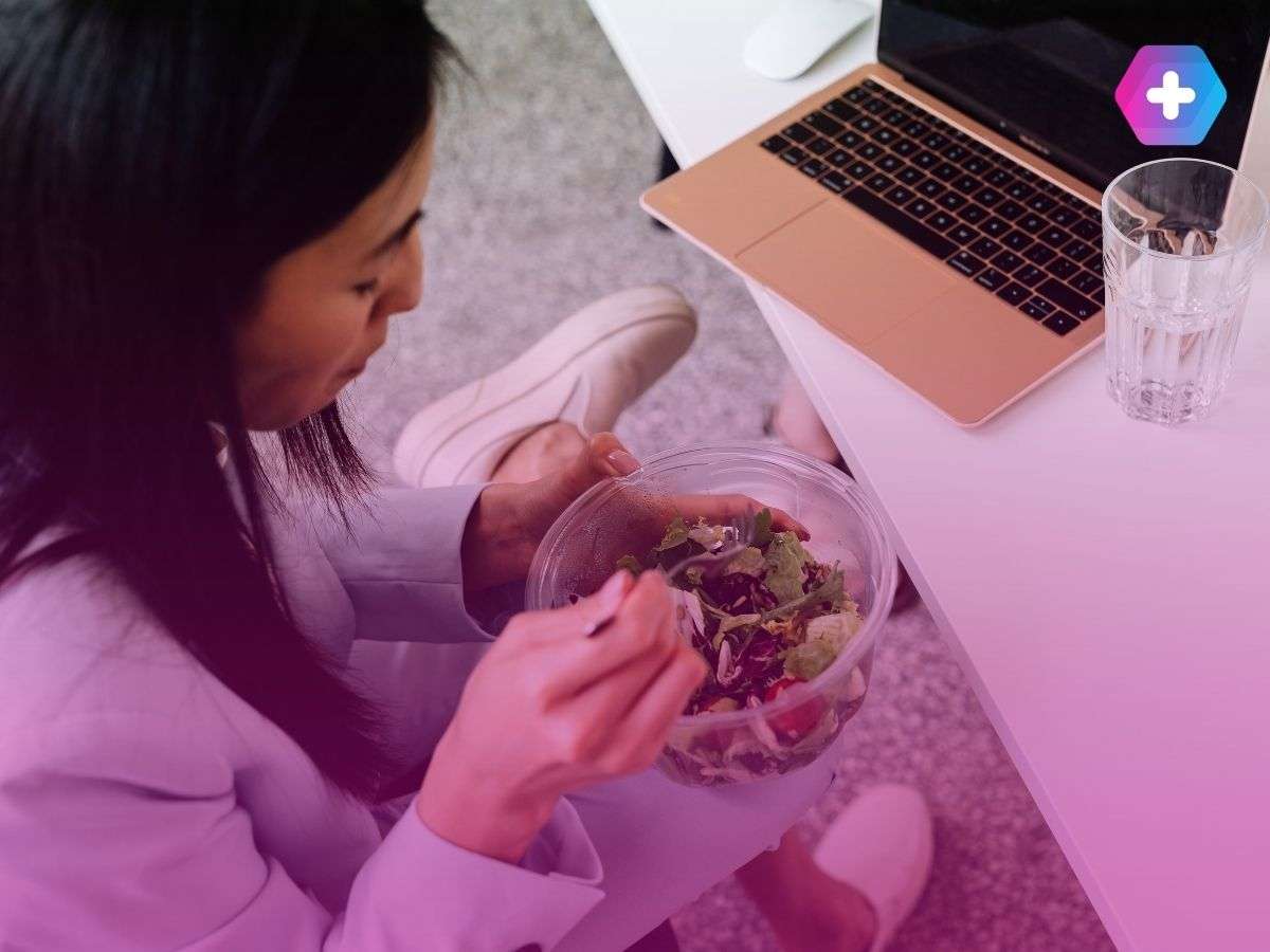 woman eating salad in front of laptop