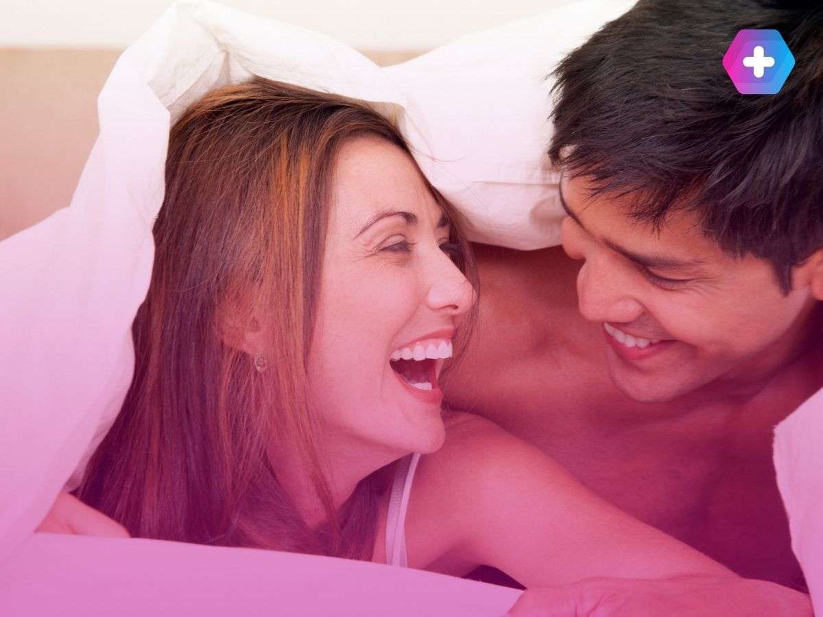 man and woman smiling under bedsheets