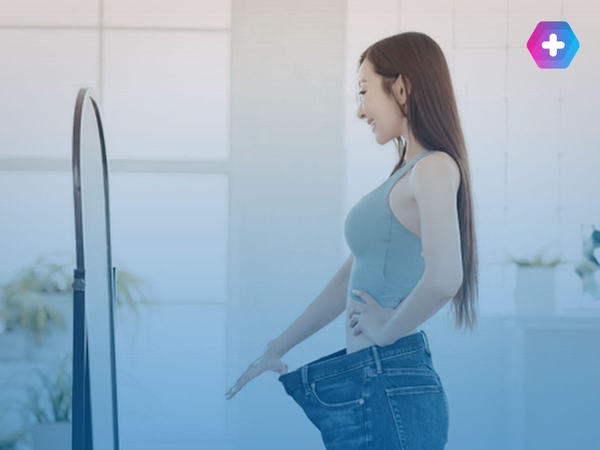 Woman viewing weight loss success in mirror in large jeans