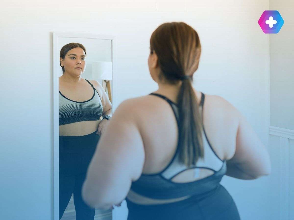 Woman looking in the mirror in gym gear