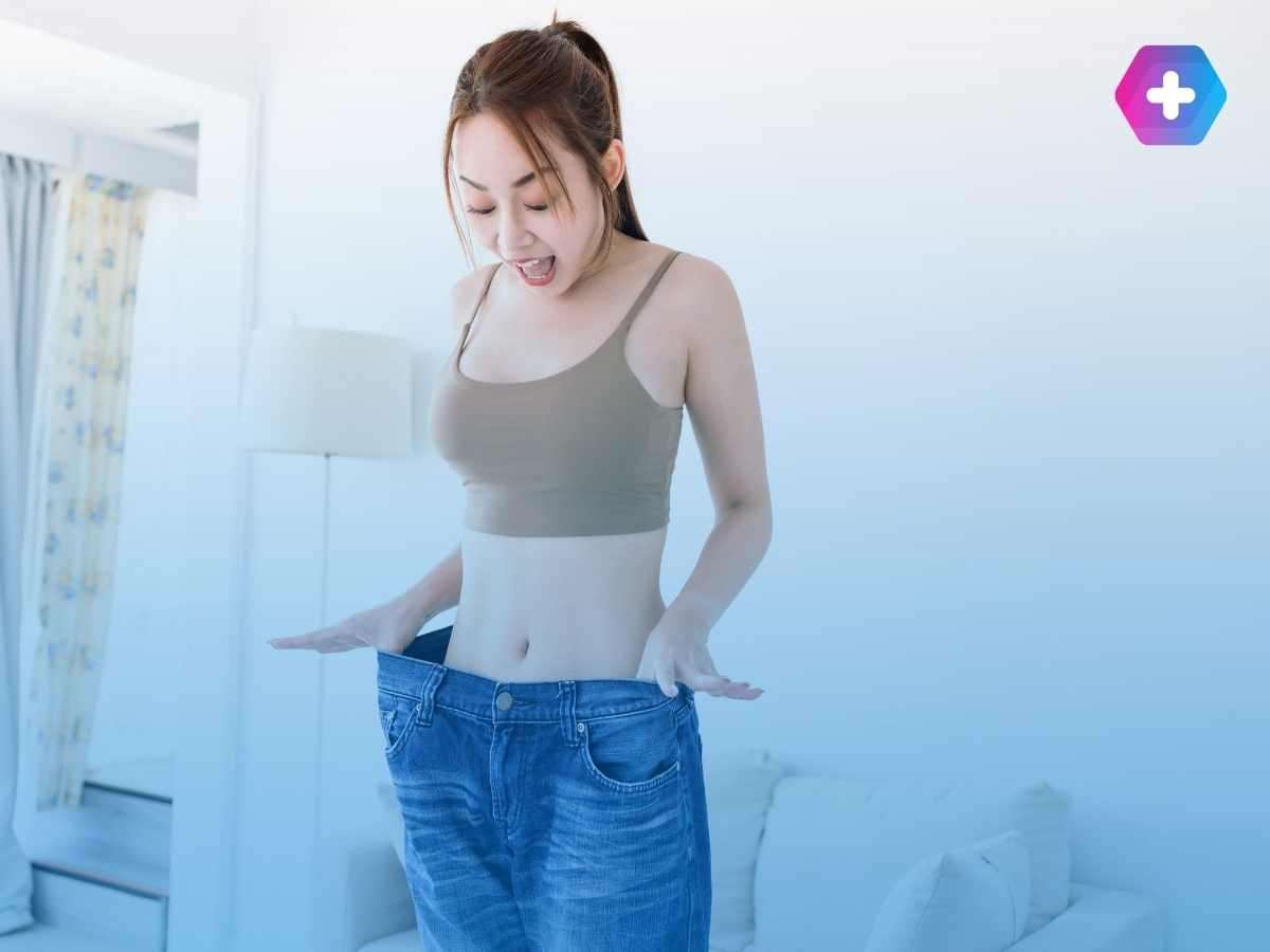 Woman looking at weight loss success in old, big jeans.