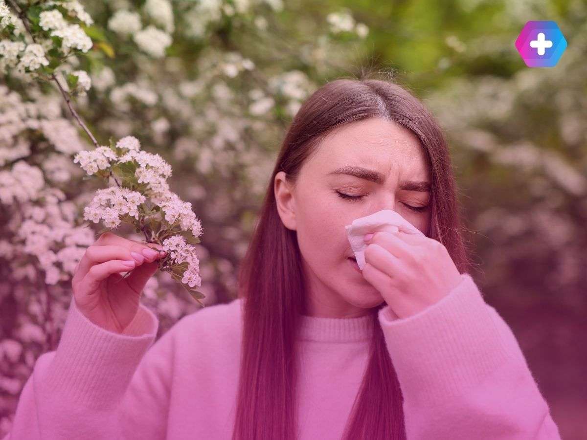young woman blowing nose with handkerchief next to flowers