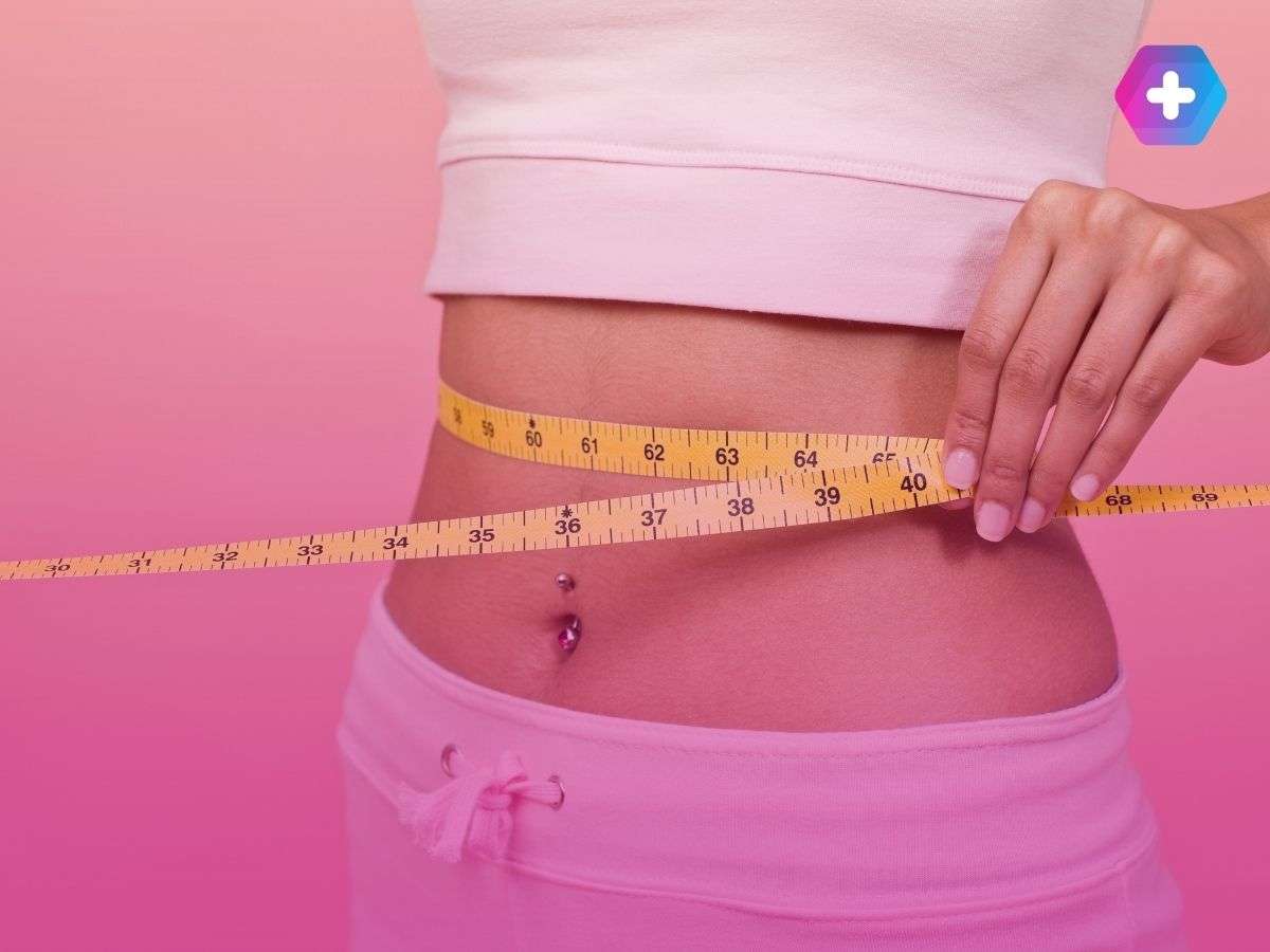 woman in pink workout gear measuring waist