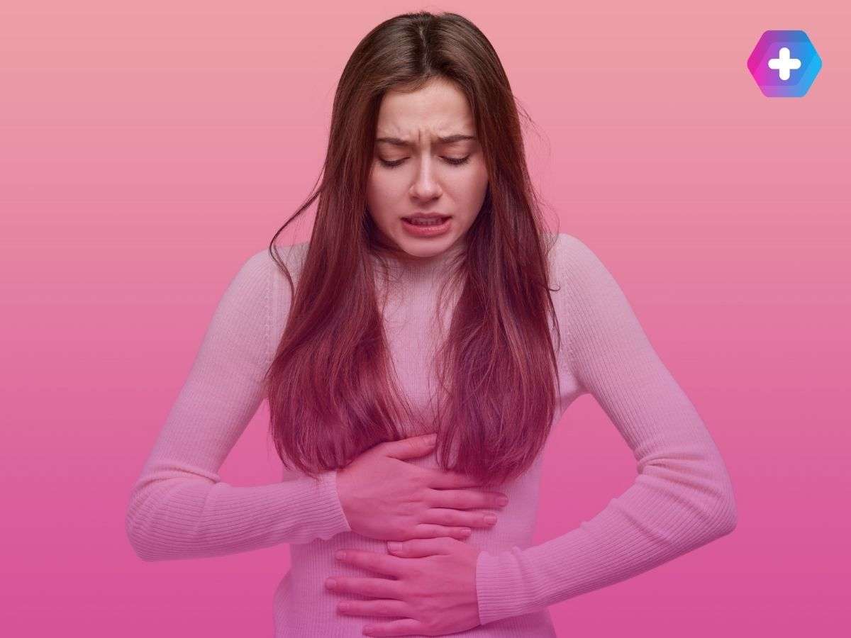 young woman clutching lower body in discomfort on pink background