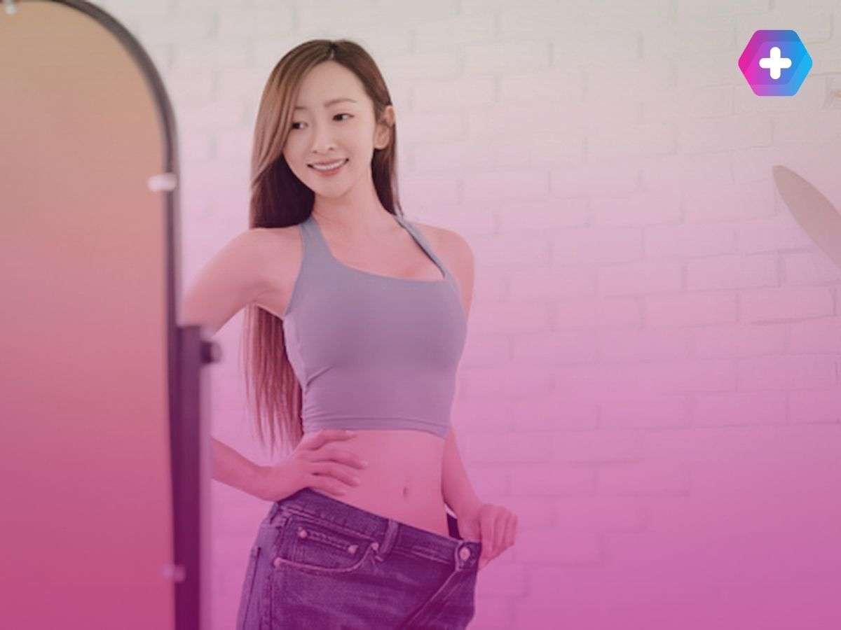 woman in green crop top and jeans looking in mirror smiling